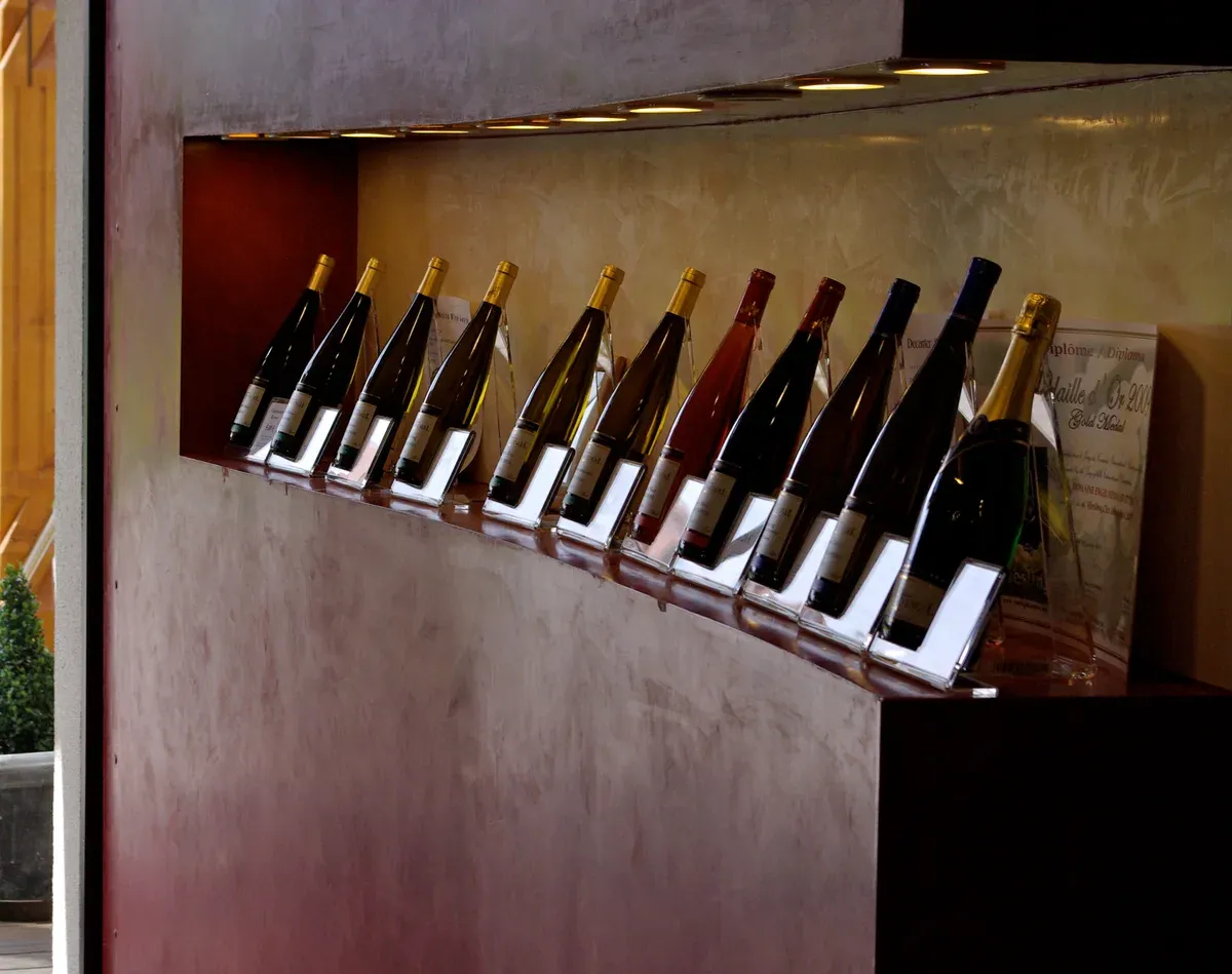 Alsatian wine bottles lined on a curved display shelf in a tasting room