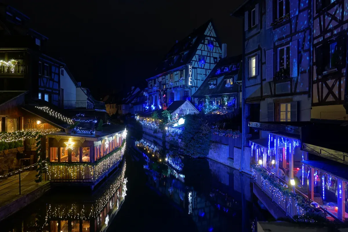 Illuminated canal houses and a boat in Petite Venise, Colmar, at night